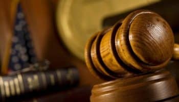 Judge's hammer on the background of the book and shield