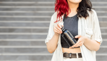 woman in front of steps holding metal reusable water bottle