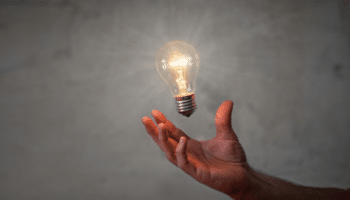 open hand with lit lightbulb floating above