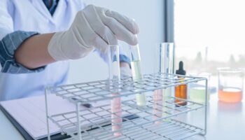 gloved hand picking up a test tube