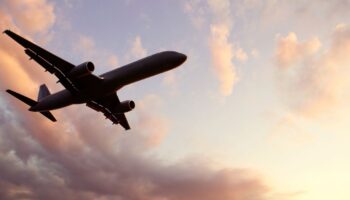 plane flying througt the clouds at sunset