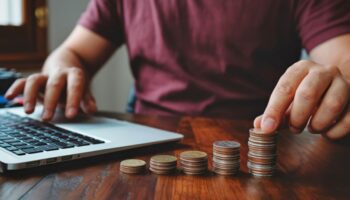 Man budgeting at a desk with a laptop and coins
