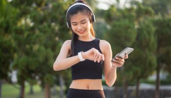 Jogging woman with headphones looking at her smart watch