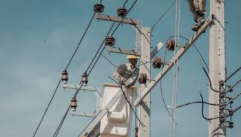 Man fixing electrical wires on telephone pole